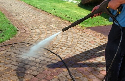 man power washing cobblestone with Dark Horse Landscaping in Boca Raton florida